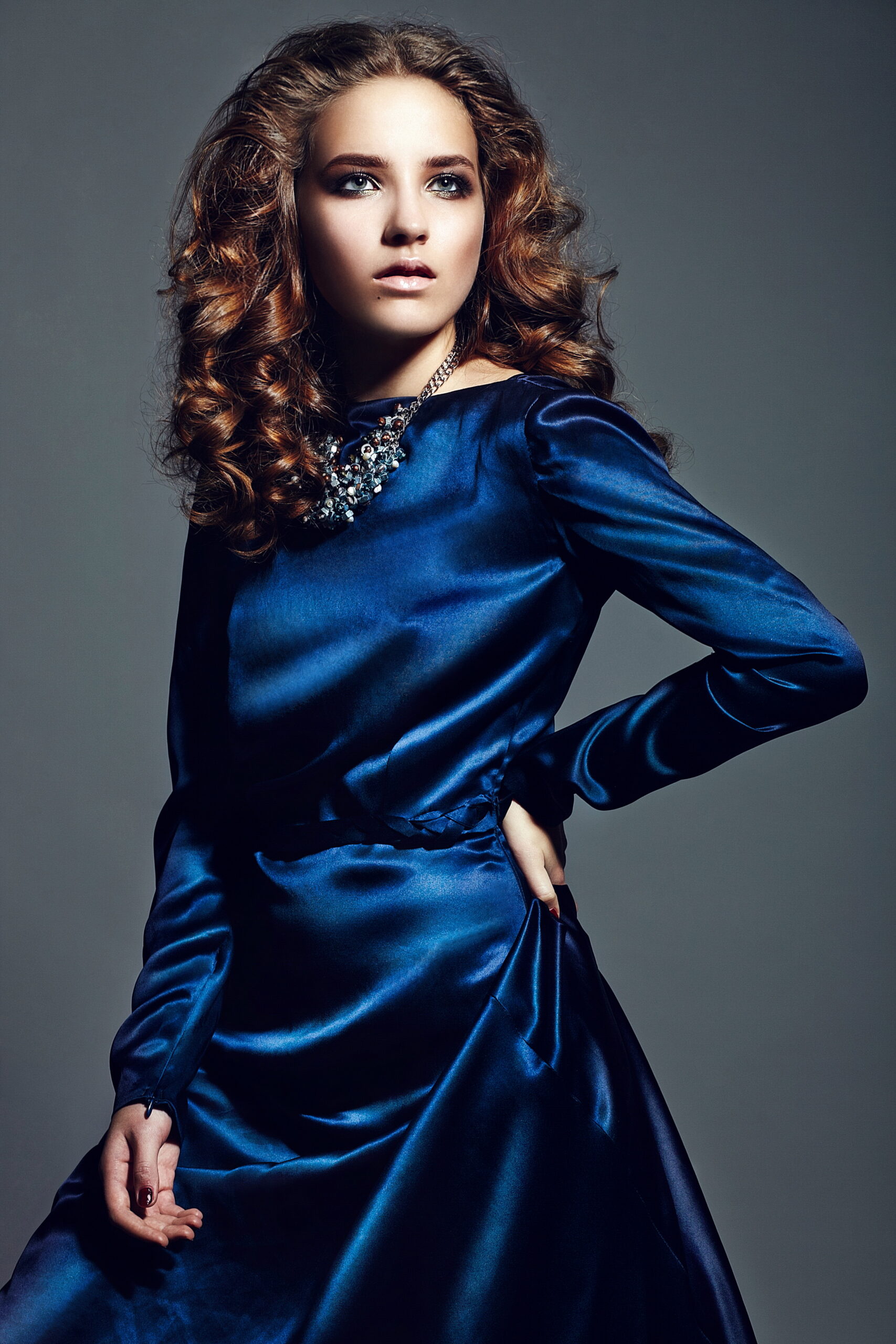 High fashion look.glamor portrait of beautiful sexy stylish brunette Caucasian young woman model with bright makeup, with healthy curly hair in bright blue dress in studio accessories with royal blue dress